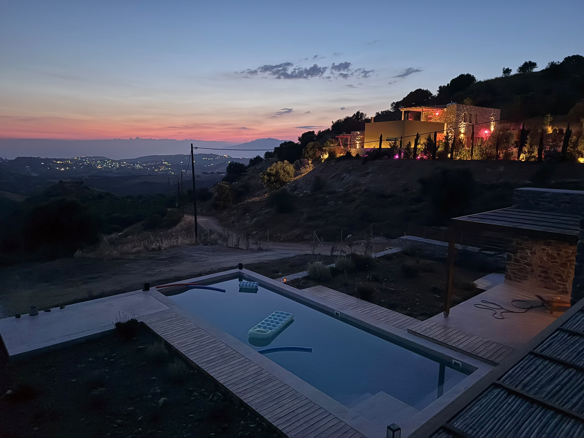 Pool und beleuchtetes Haus auf Kreta in Hanglage bei Abenddämmerung